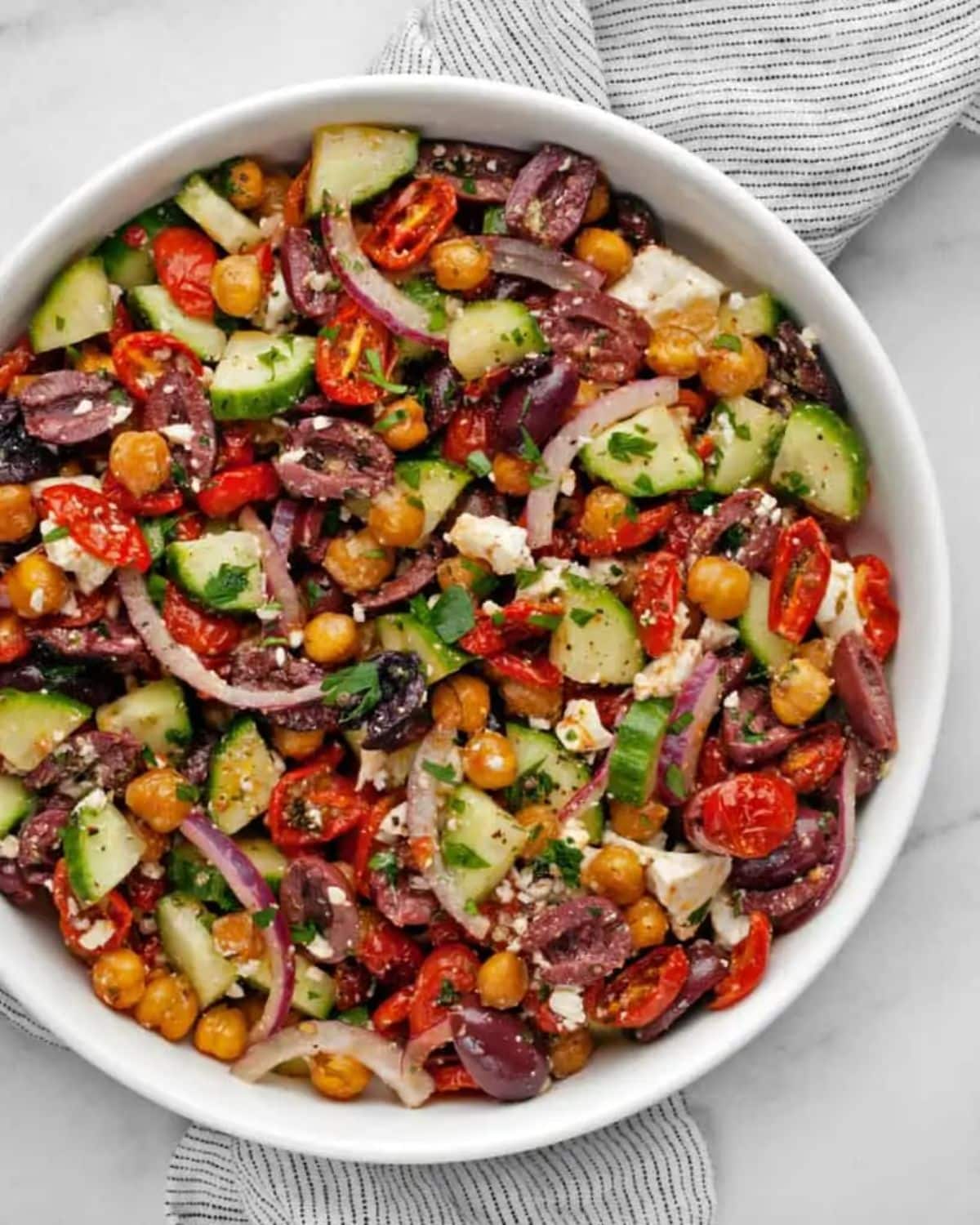 Healthy chickpea greek salad in a white bowl.