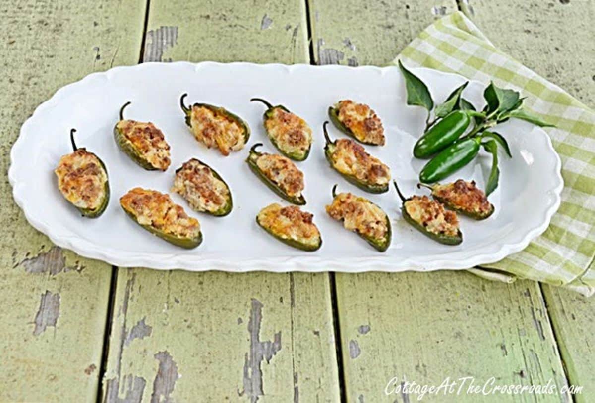 Scrumptious sausage and cheese stuffed jalapeño peppers on a white tray.