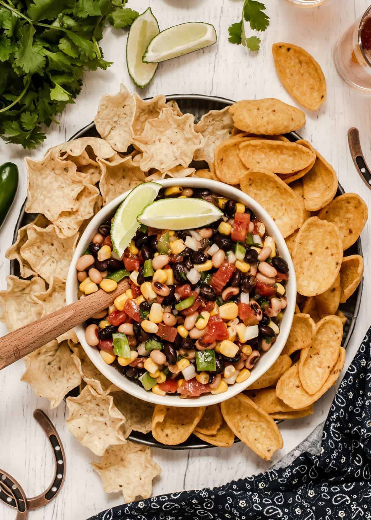 Healthy bean and corn salsa in a bowl with  chips on a tray.