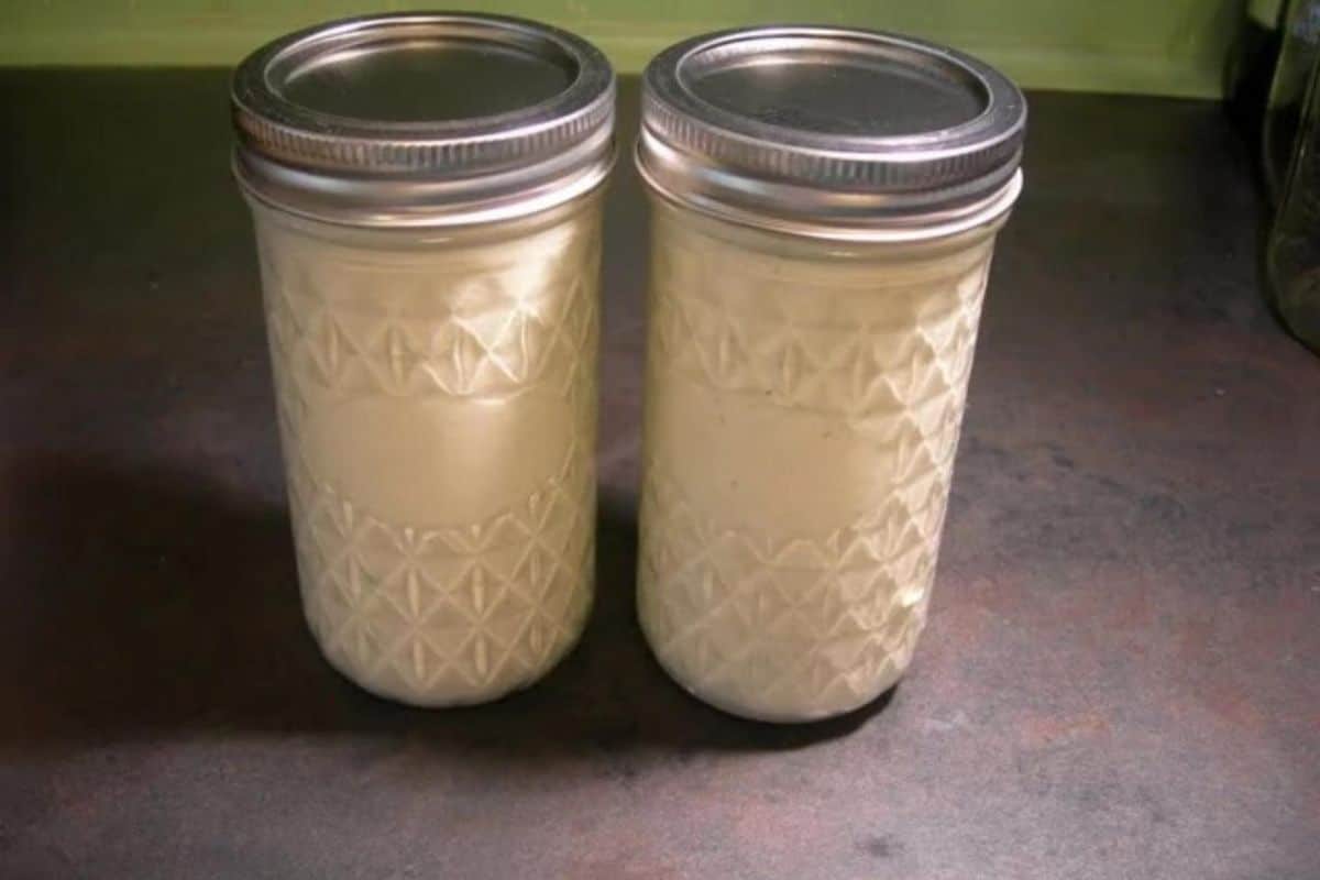 Creamy cucumber salad dressing in two glass jars.