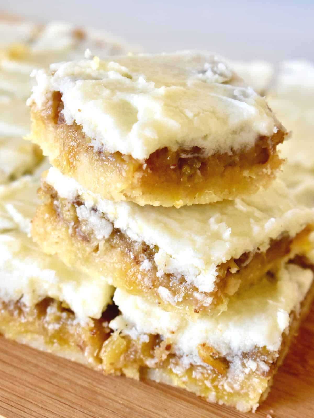 A pile of hawaiian pecan and pineapple bars on a wooden tray.