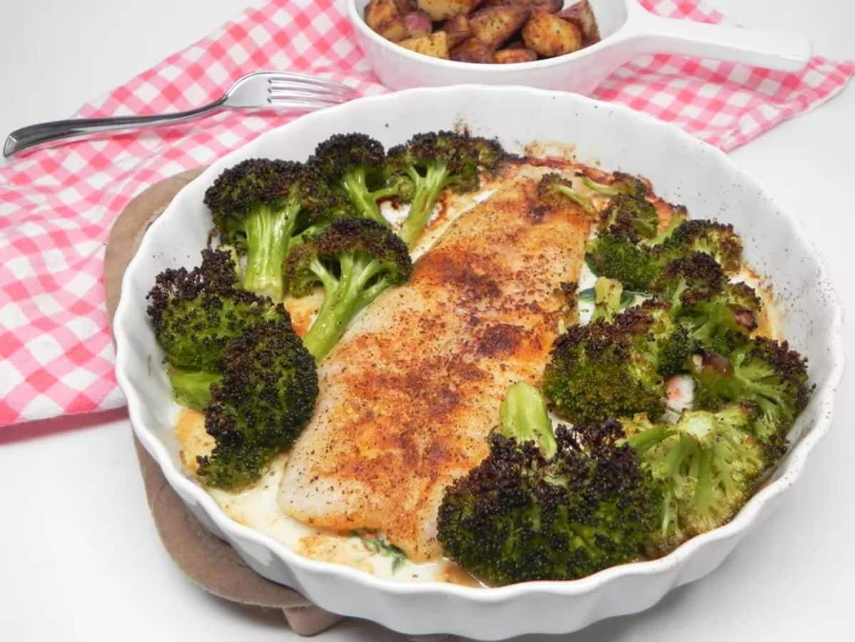 Delicious old bay tilapia and broccoli in a white bowl.