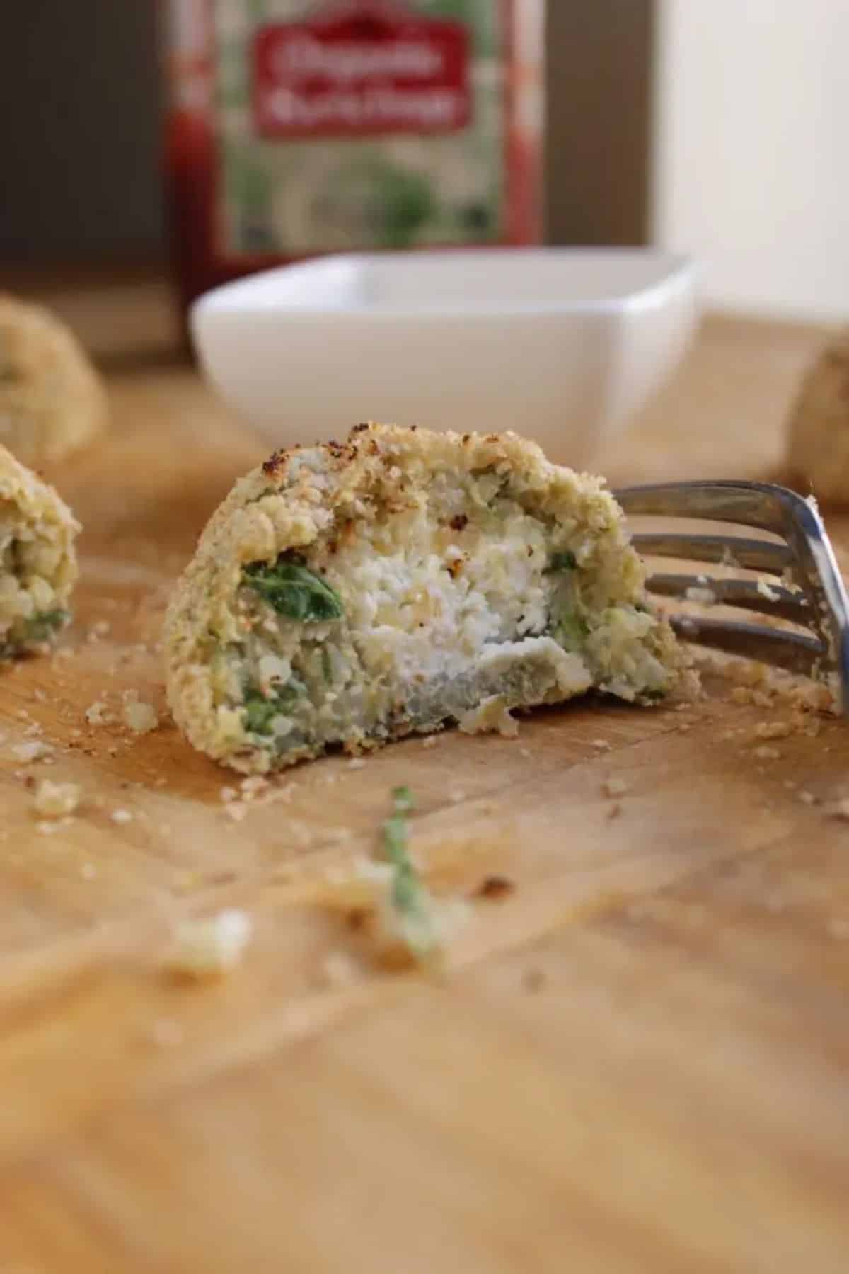 Sliced goat cheese stuffed quinoa nugget on a wooden table.