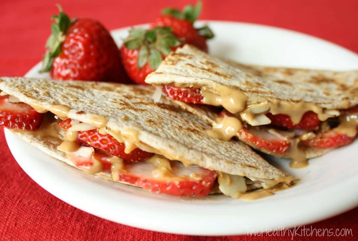Mouth-watering strawberry peanut butter quesadillas on a white plate.