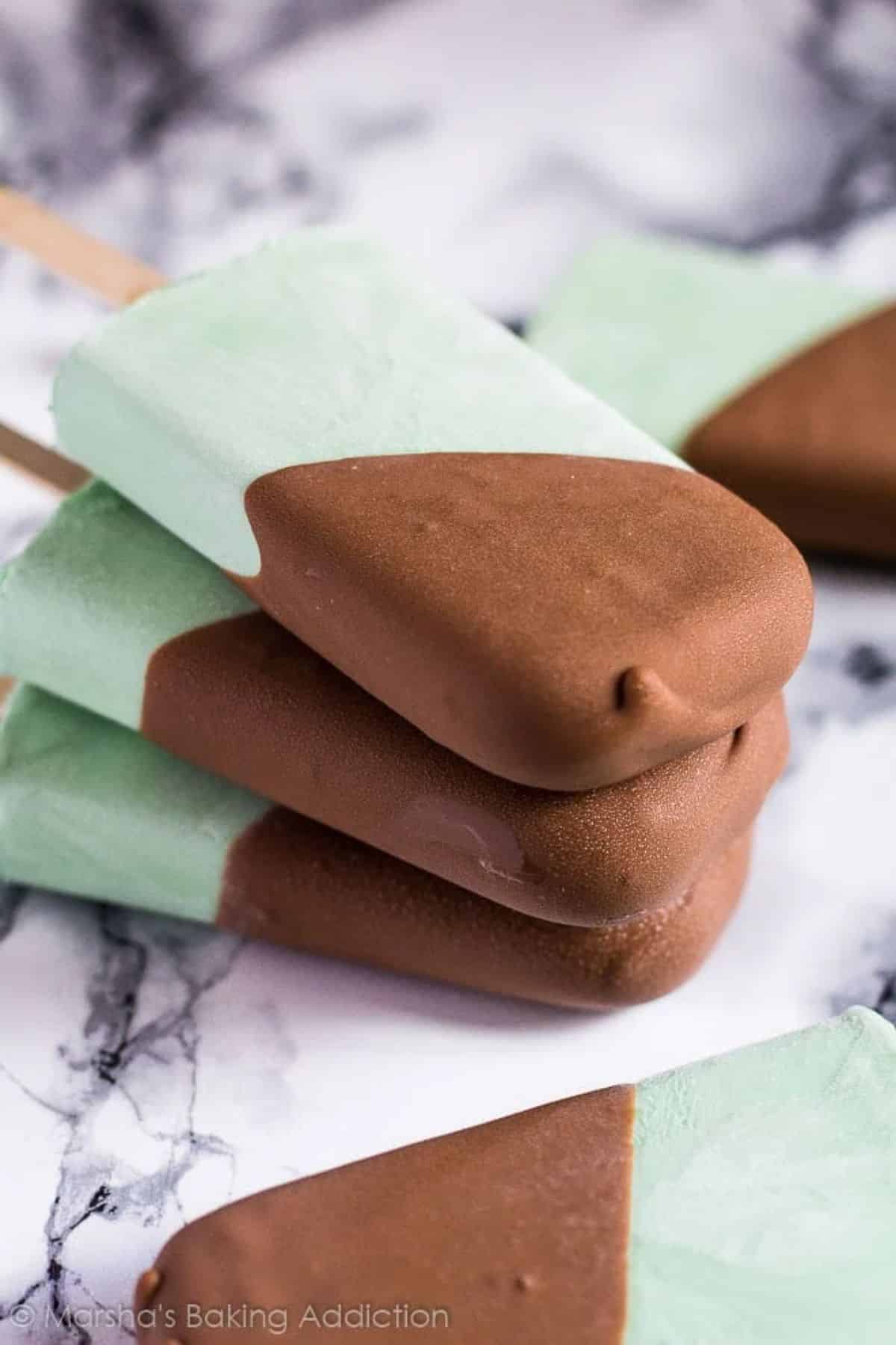 A crunchy mint chocolate chip greek yogurt popsicles on a tray.