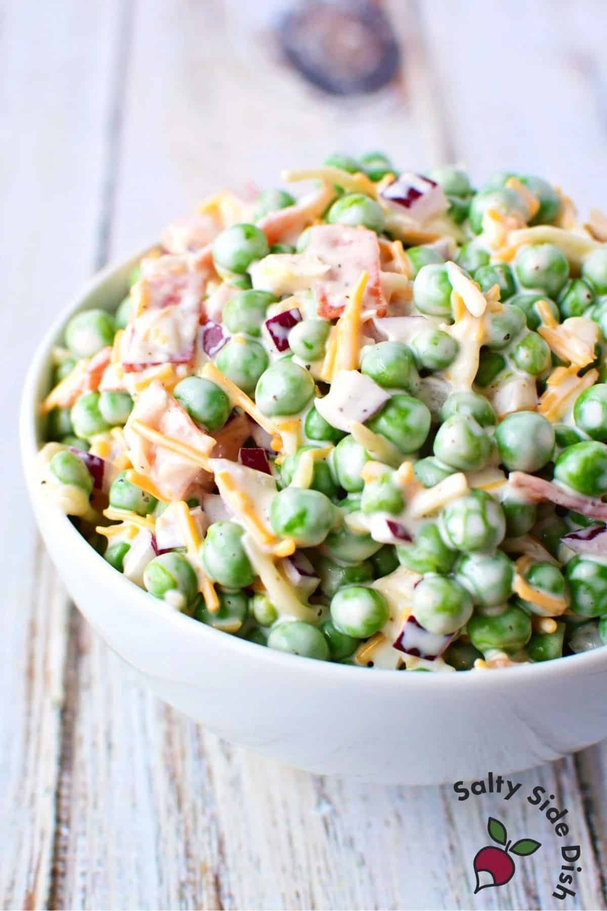 Fresh pea salad with red onions in a white bowl.