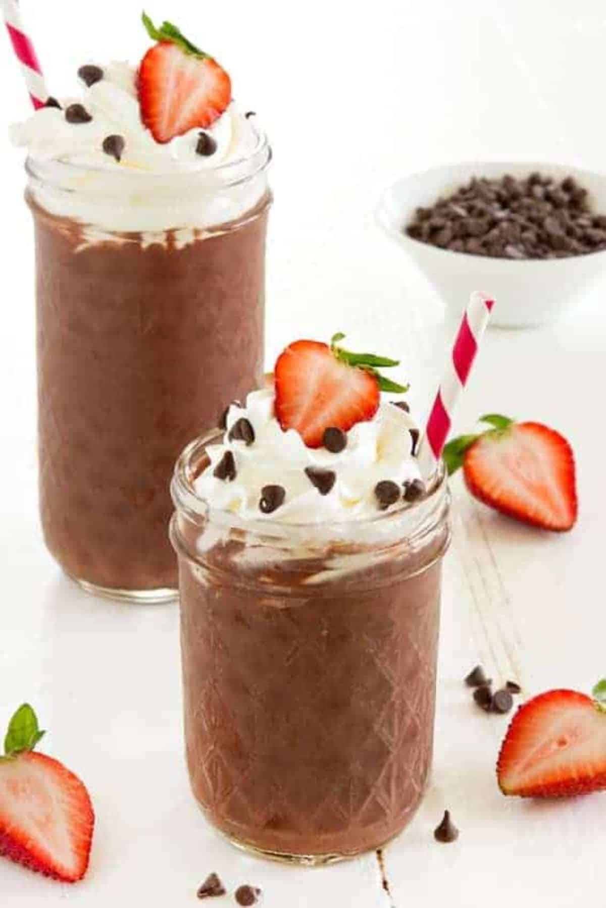 Fresh strawberry chocolate dessert smoothies in glass jars with straws.