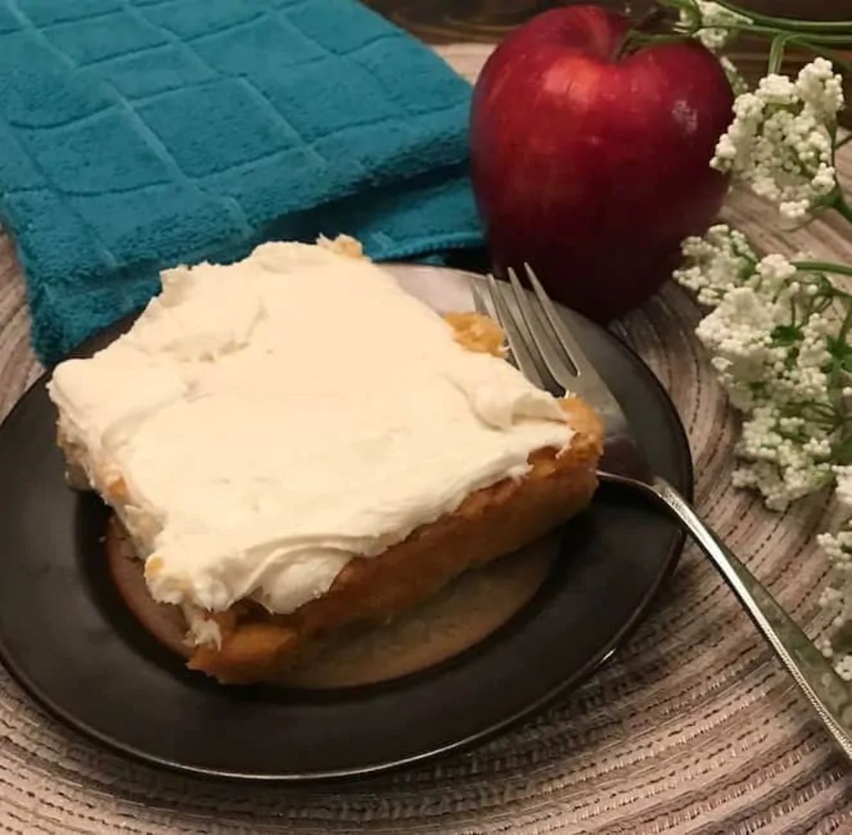 A piece of two-ingredient apple cakeon a black plate with a fork.