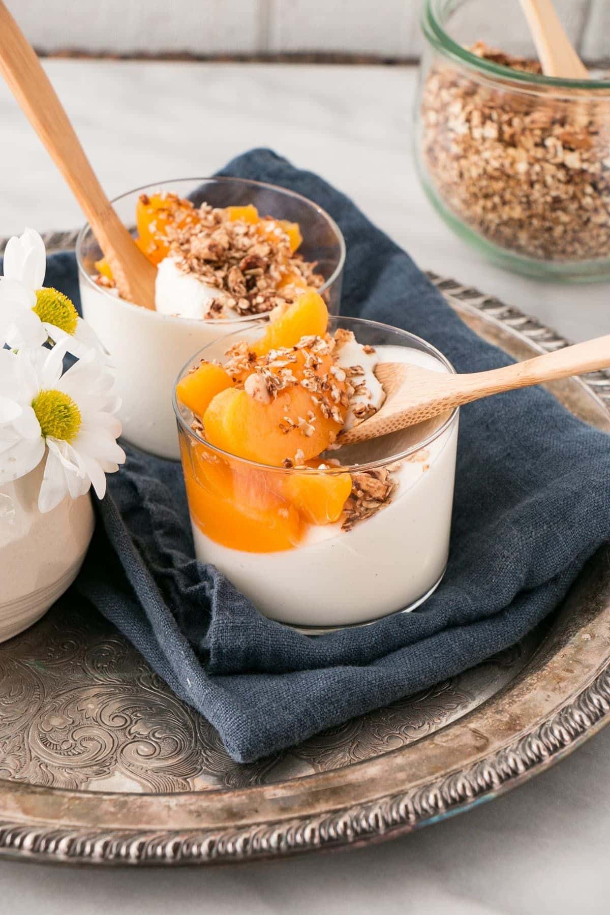 Flavorful and sweet cinnamon peach panna cotta in glass cups with wooden spoons.