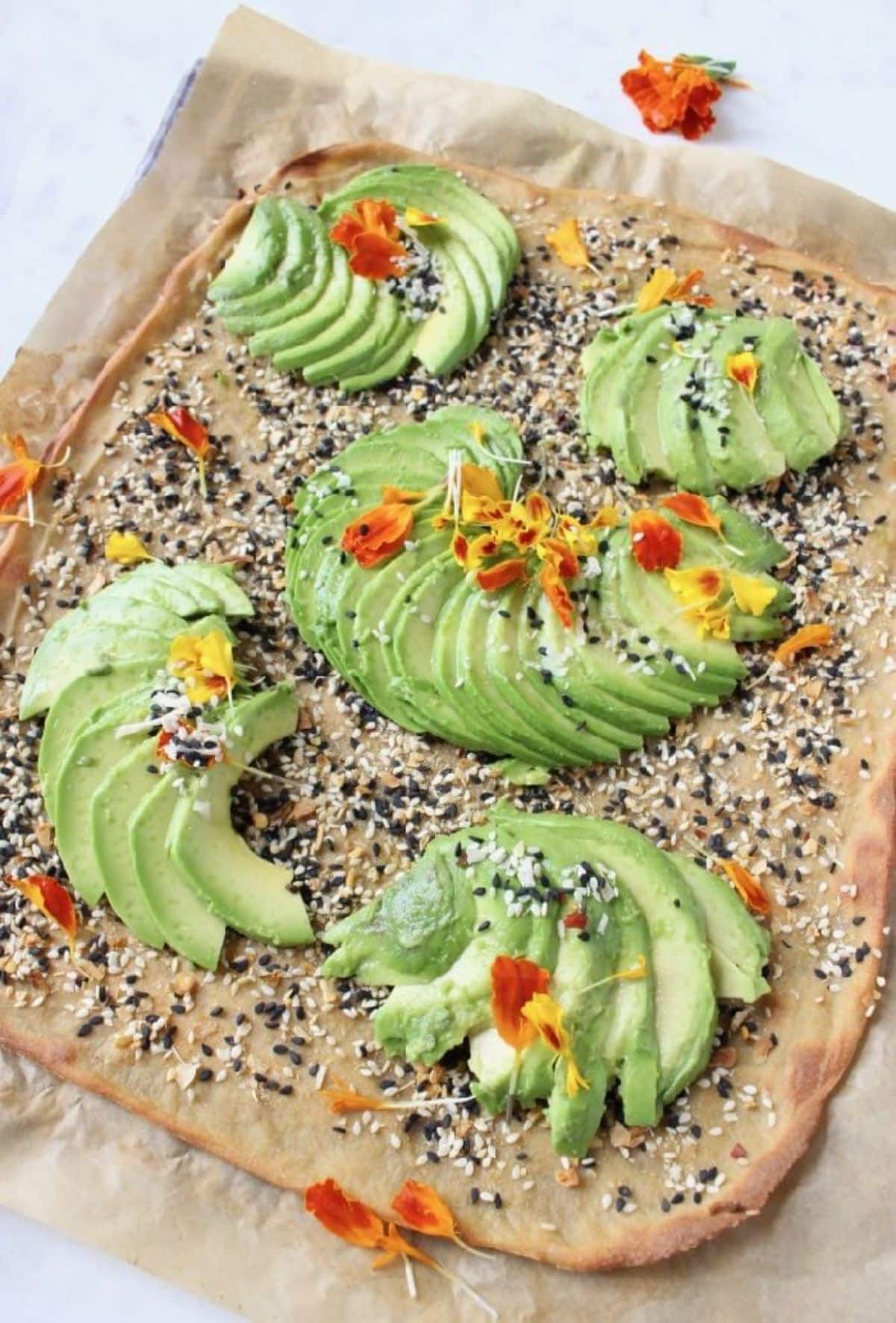 Scrispy quinoa flatbread with sliced avocado on a baking tray.