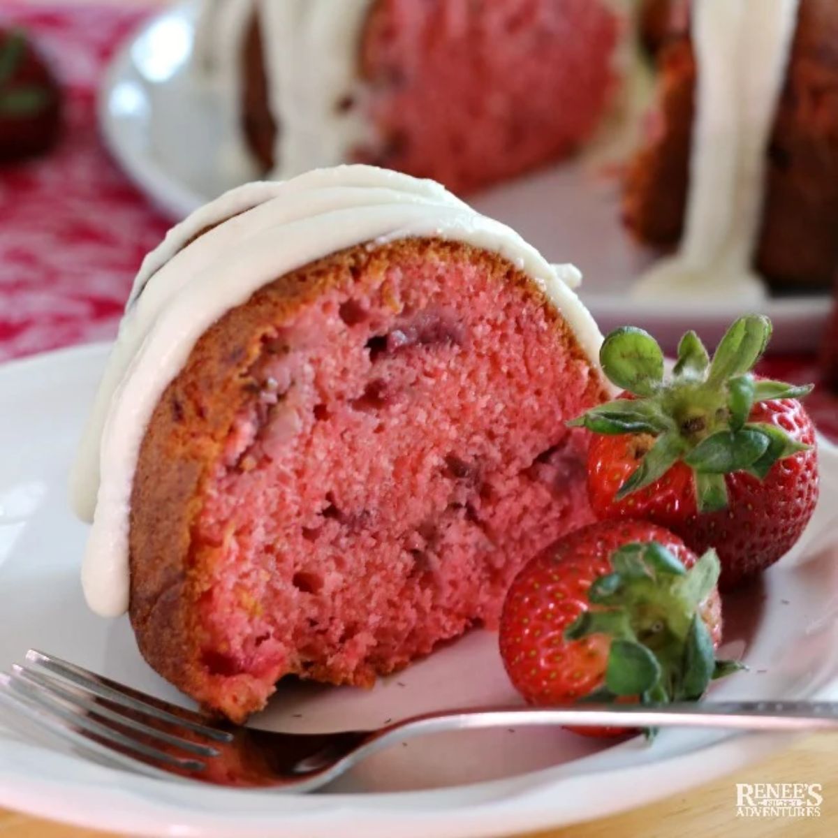 A piece of strawberry bundt cake on a white plate with a fork.