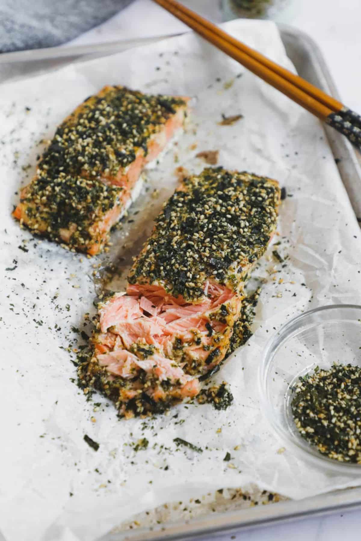 Two pieces of baked furikake salmon with kewpie mayo on a baking tray.
