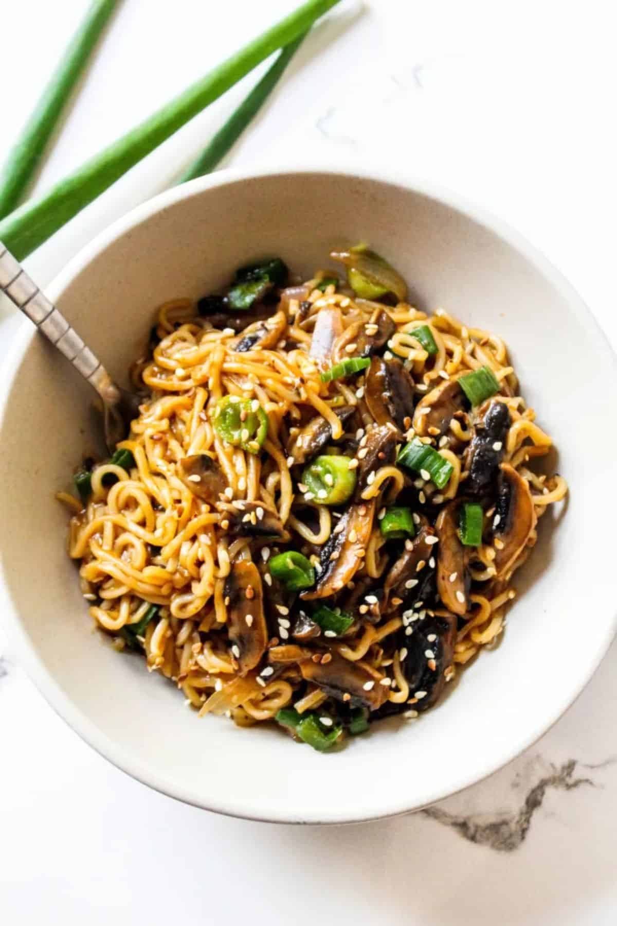 Healthy mushroom ramen noodles in with a fork in a white bowl.