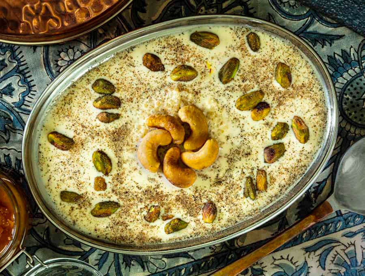 Scrumptious indian pudding in a bowl garnished with nuts.