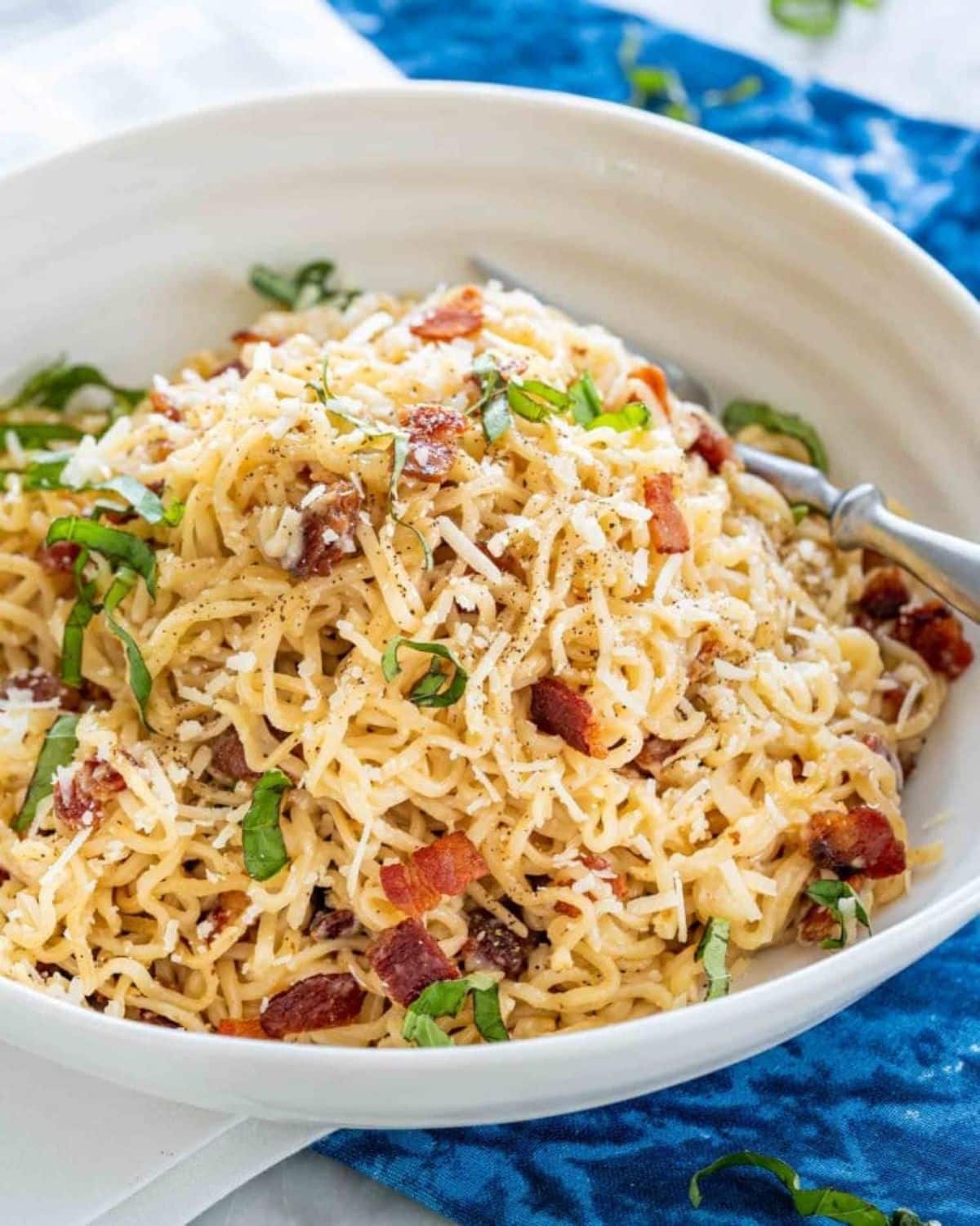 Healthy ramen carbonara in a white bowl with a fork.