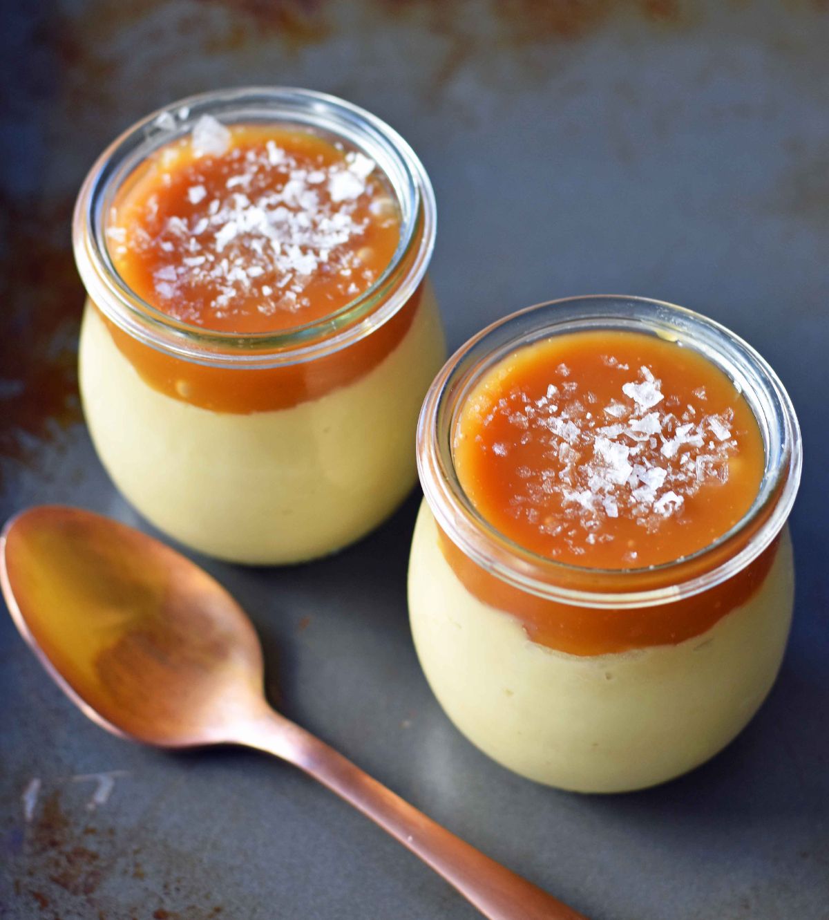 Mouth-watering butterscotch budinos with salted caramel in two glass cups.