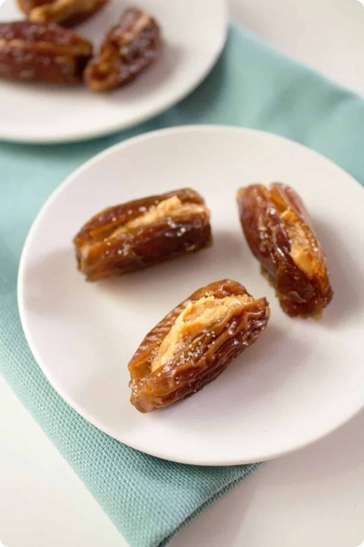 Tasty nut butter stuffed salty dates on a white plate.