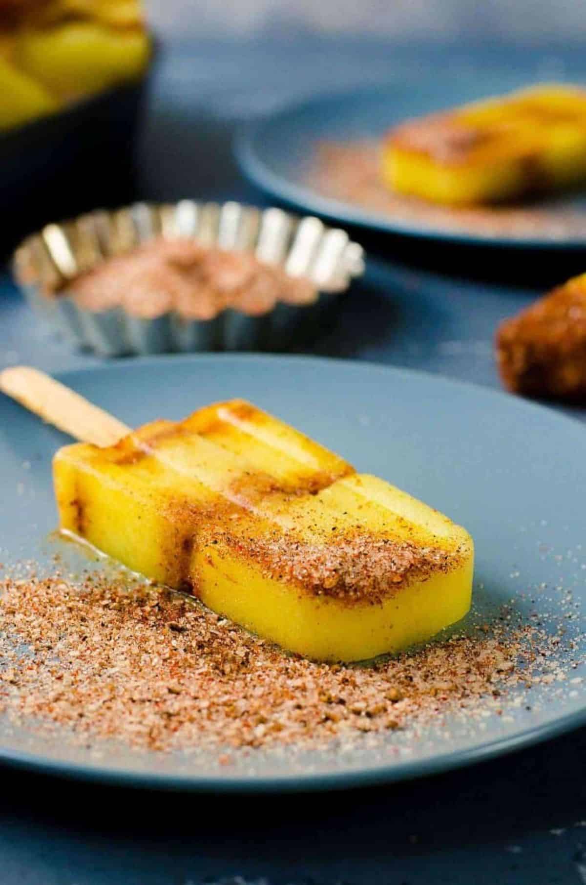 Mouth-watering spicy pineapple paleta on a blue plate.
