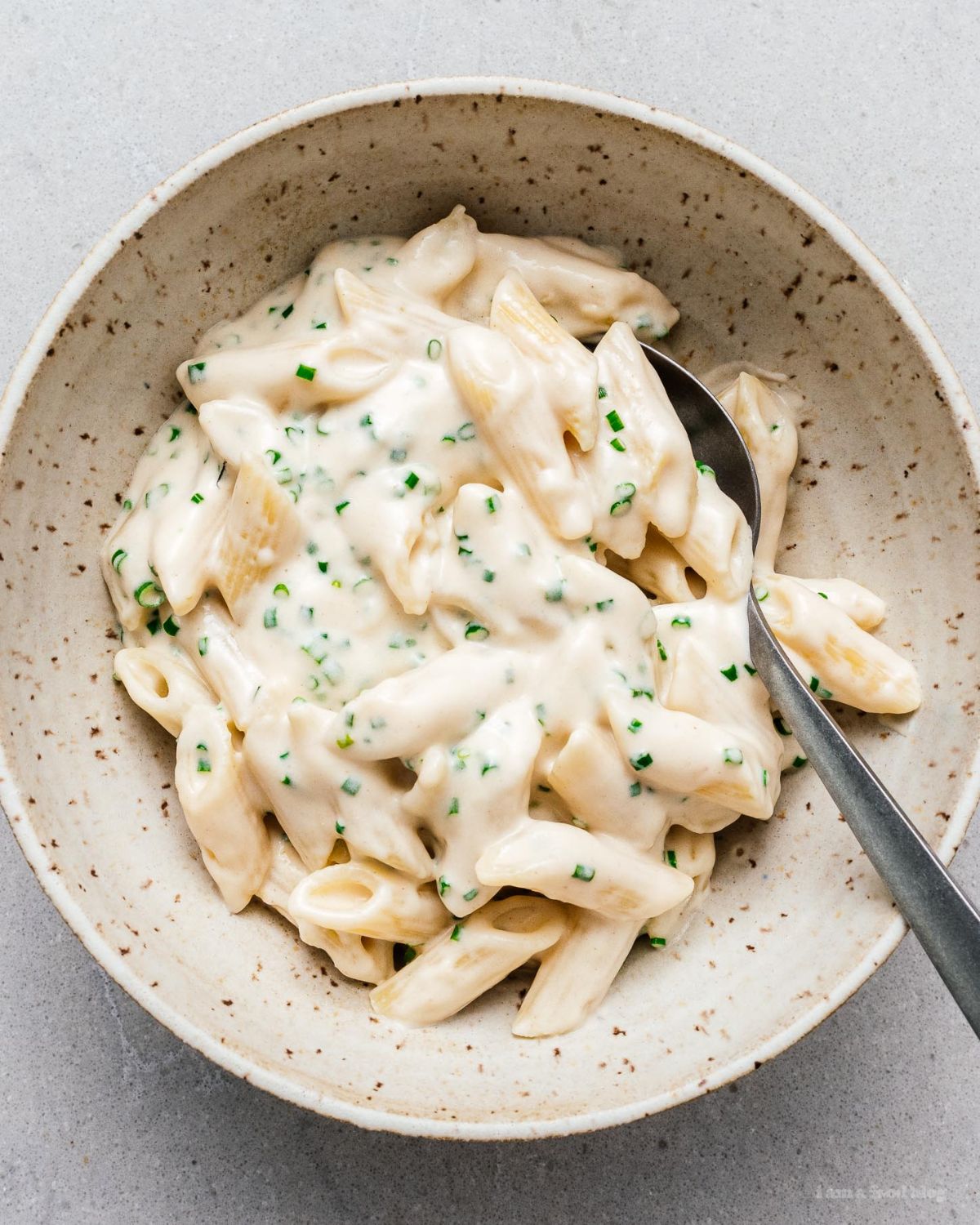 Juicy sour cream and onion pasta in a gray bowl with a spoon.