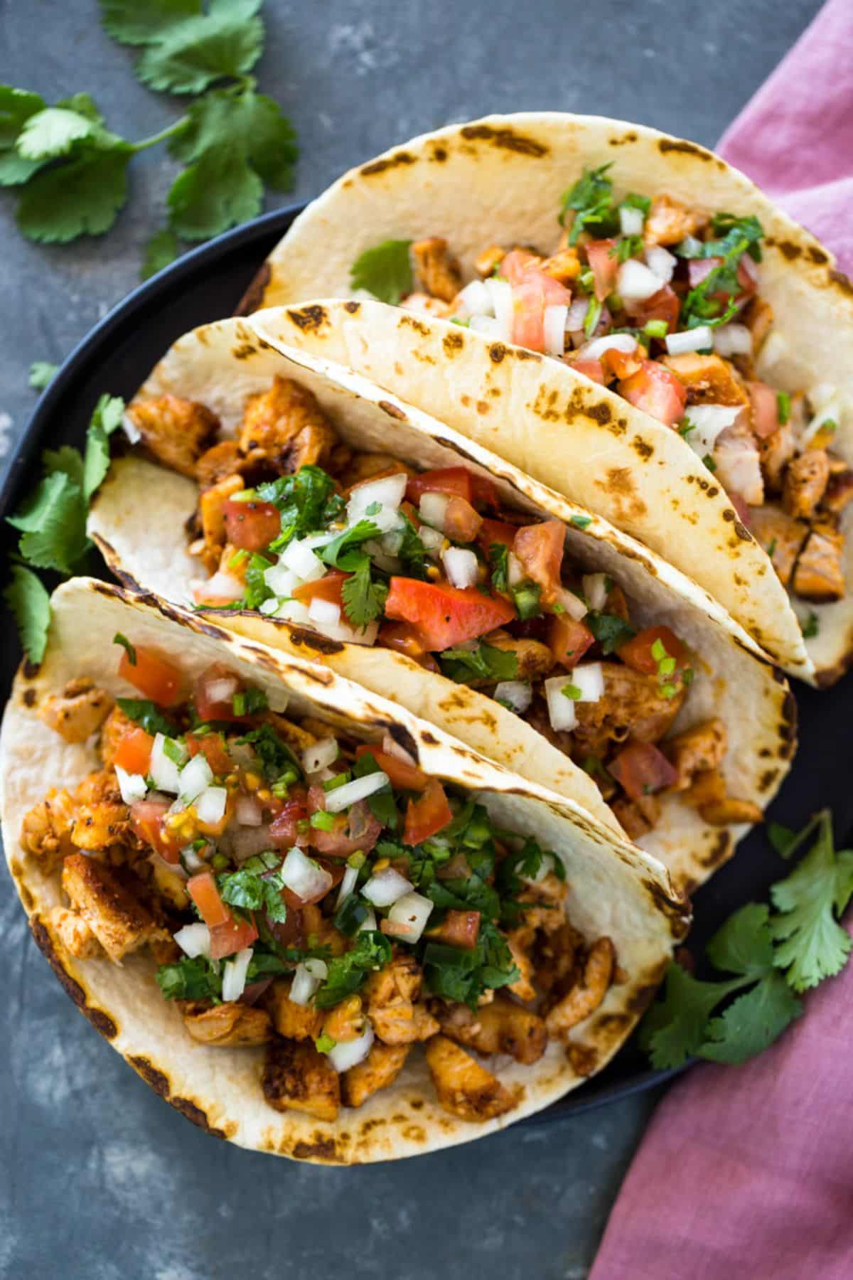 Scrumptious easy 20-minute chicken tacos on a black tray.