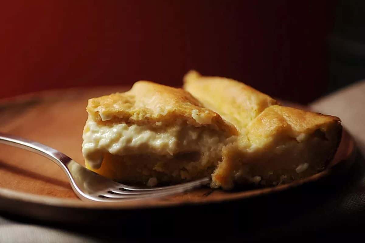 A piece of custard spoon bread on a wooden plate.