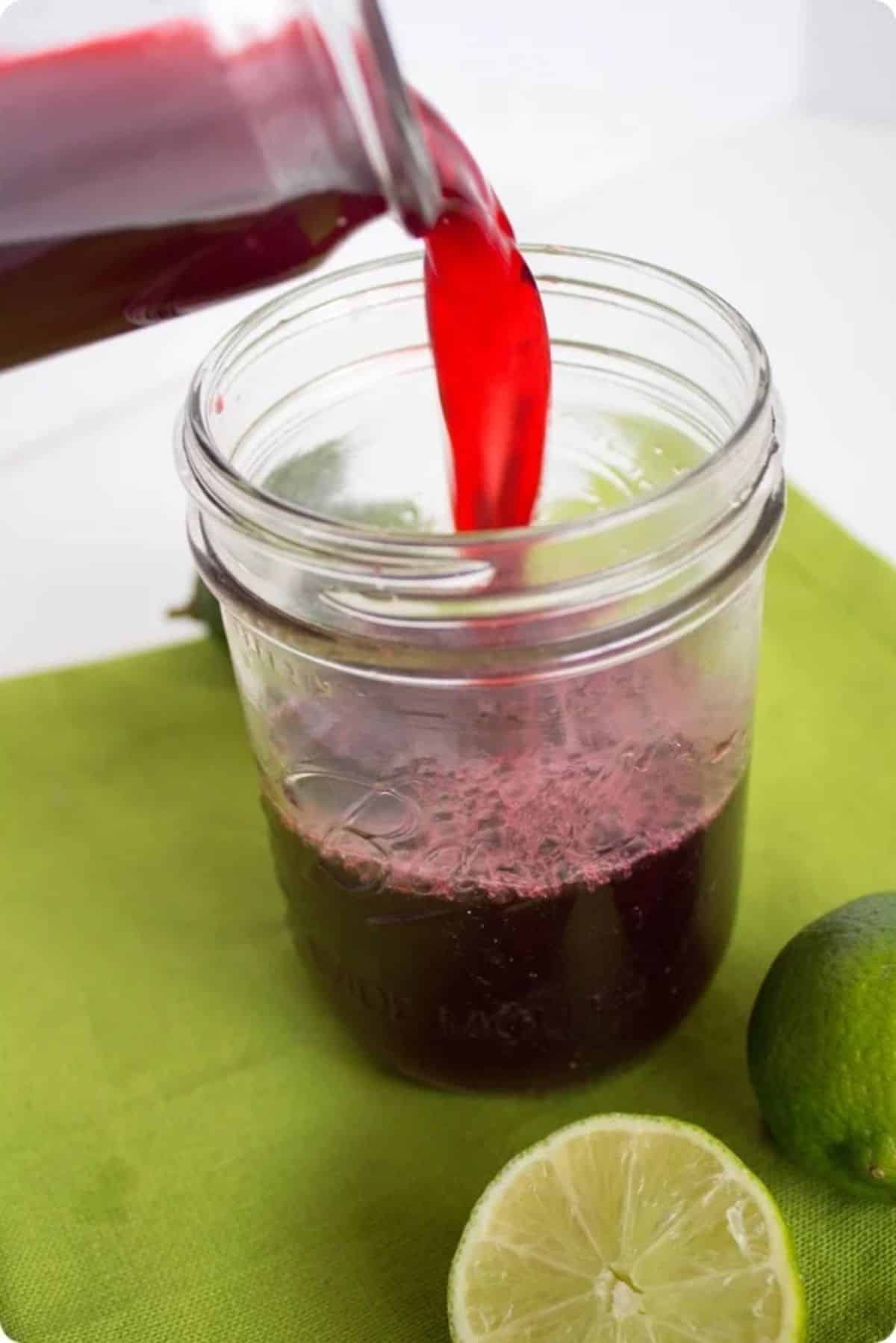 Healthy tart cherry sports drink in a glass jar poured from a bottle.