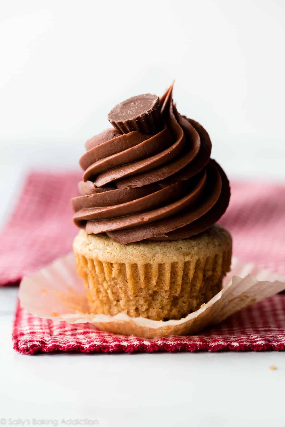 Mouth-watering peanut butter cupcake on a red tablecloth.
