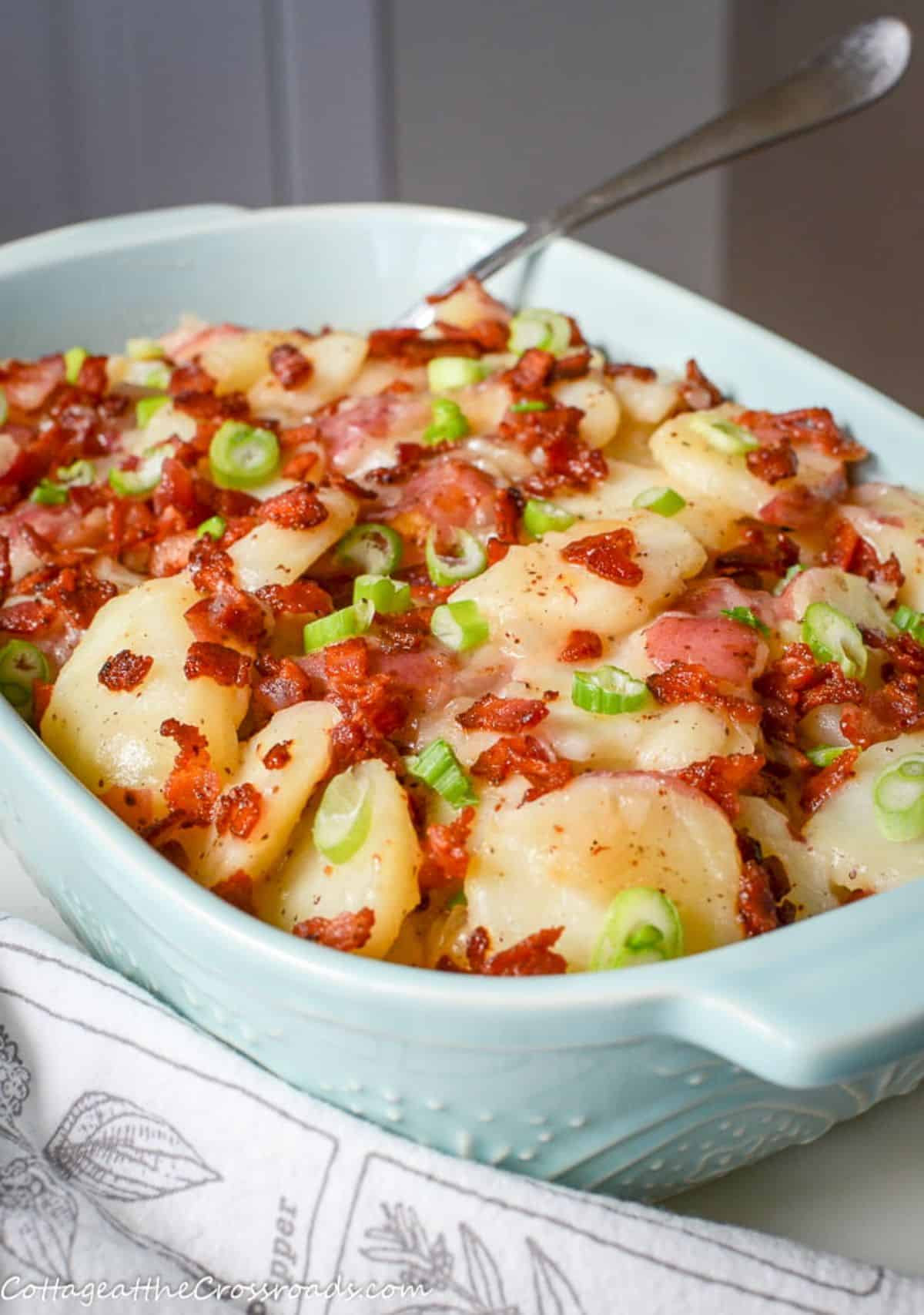 Delicious warm german potato salad with bacon in a blue casserole.