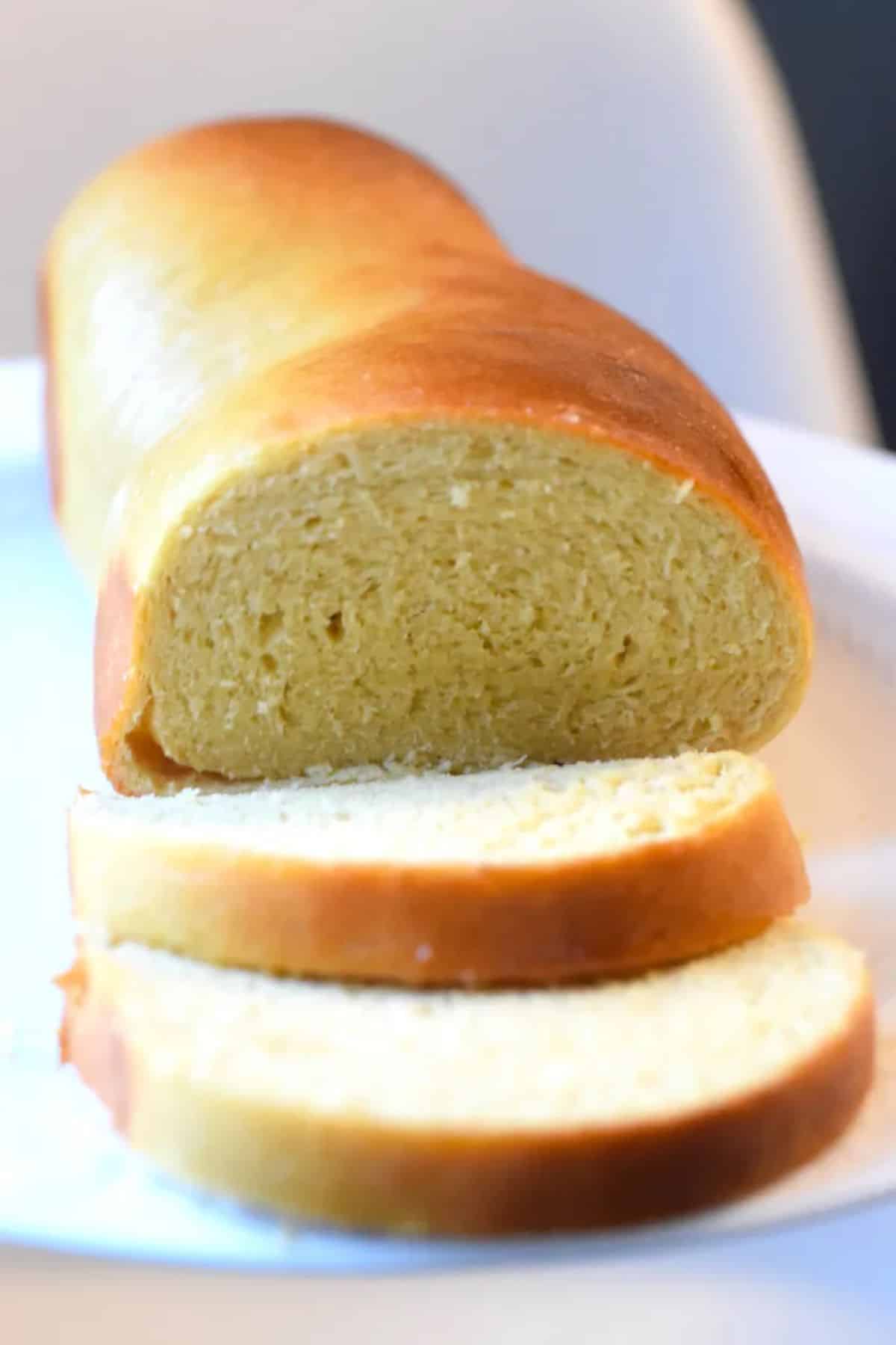 Partially sliced egg white bread on a plate.