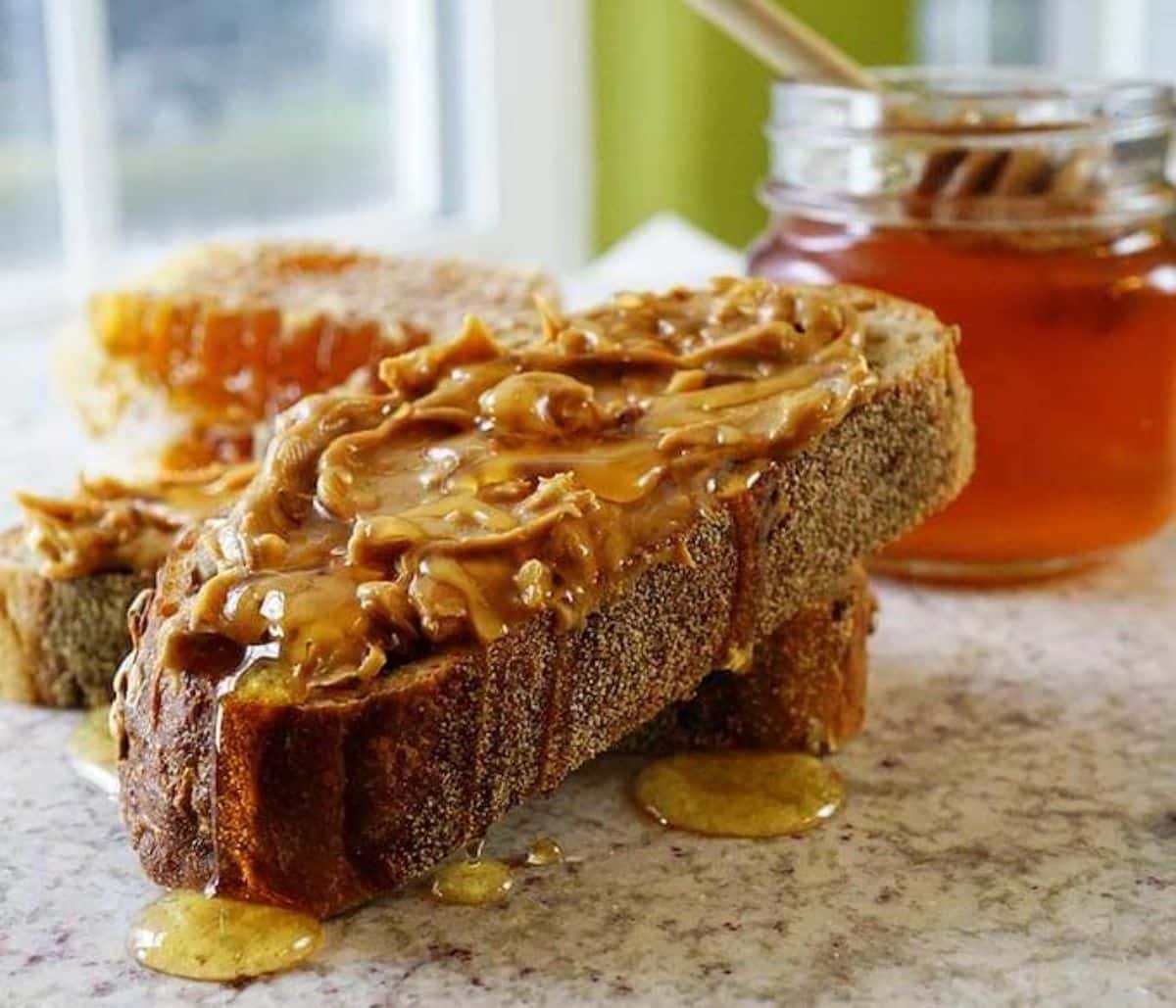 Juicy peanut butter and honey sandwich on a table.