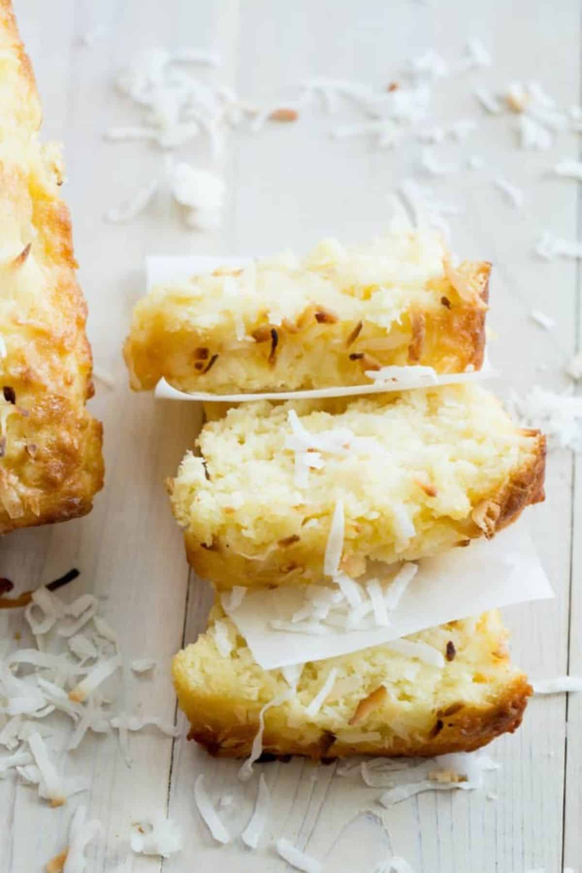 Three slices of coconut pineapple bread on a wooden table.