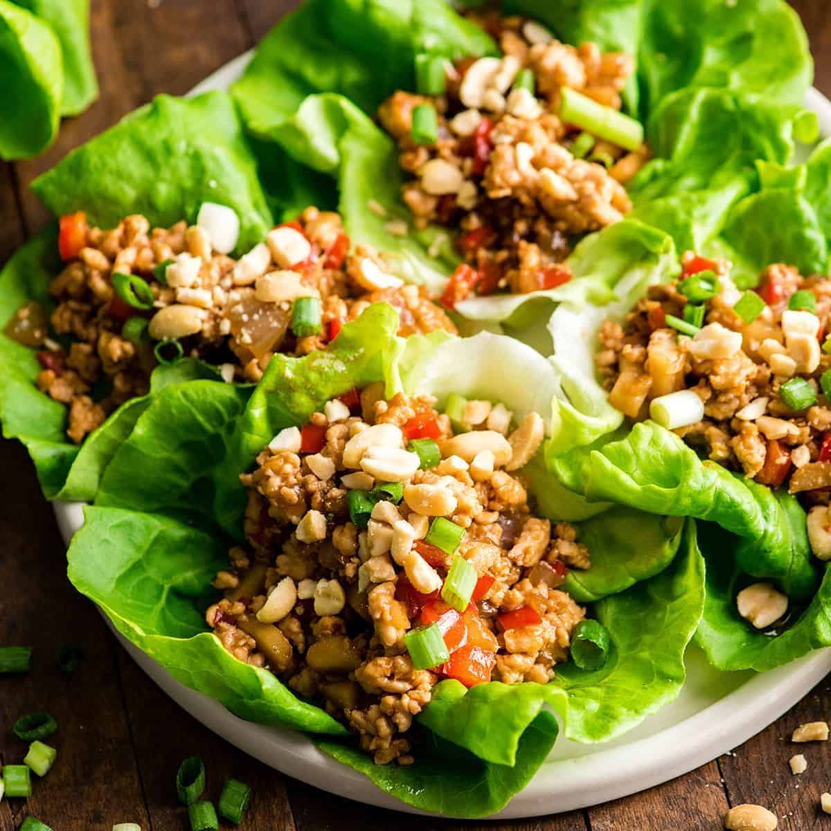 Healthy asian chicken lettuce wraps on a white plate.