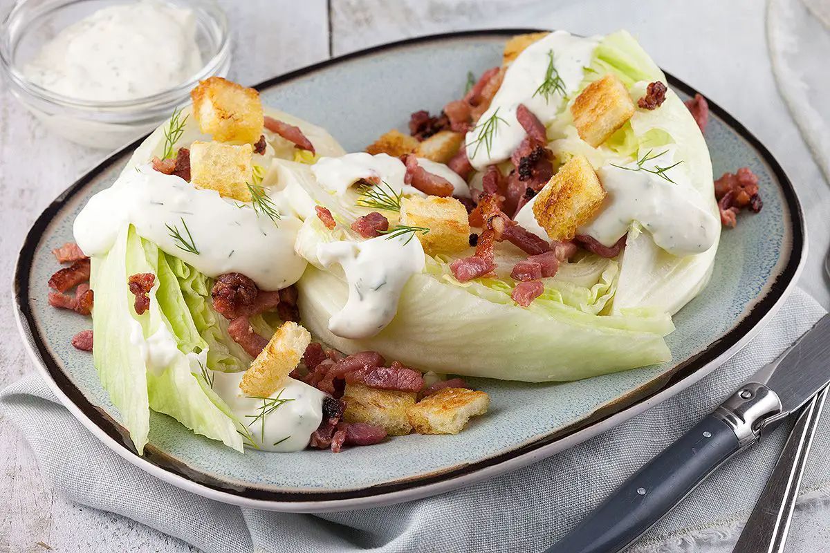 Mouth-watering iceberg wedges with grilled bacon and croutonson a gray tray.