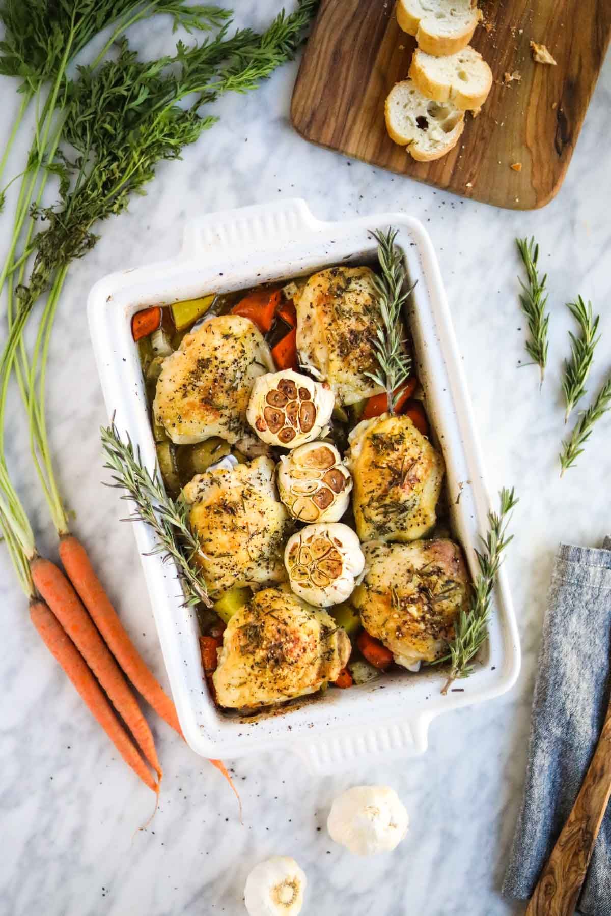 Scrumptious roasted chicken thighs and vegetables in a white casserole.