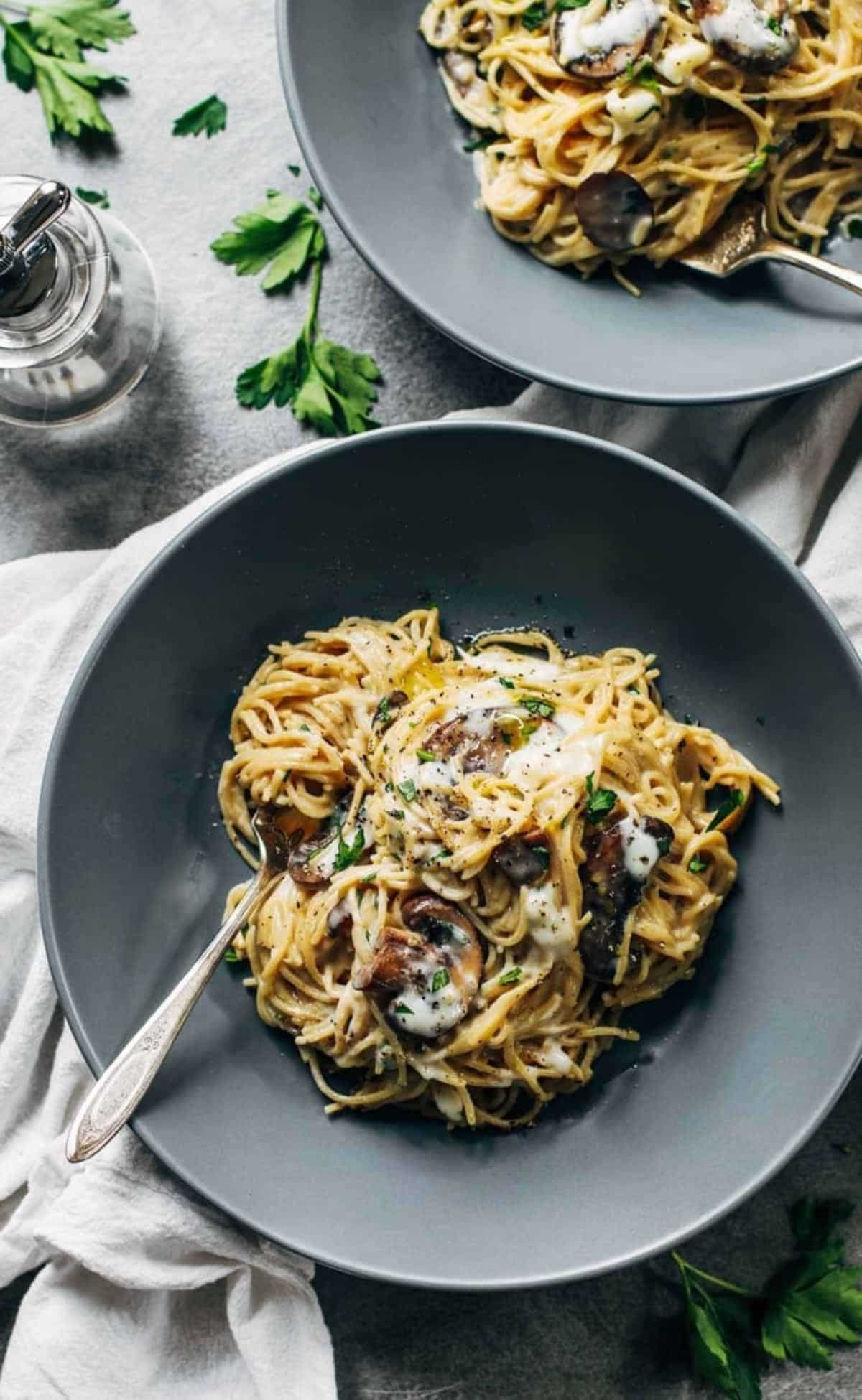 Flavorful creamy garlic herb mushroom spaghetti in a gray bowl with a fork.