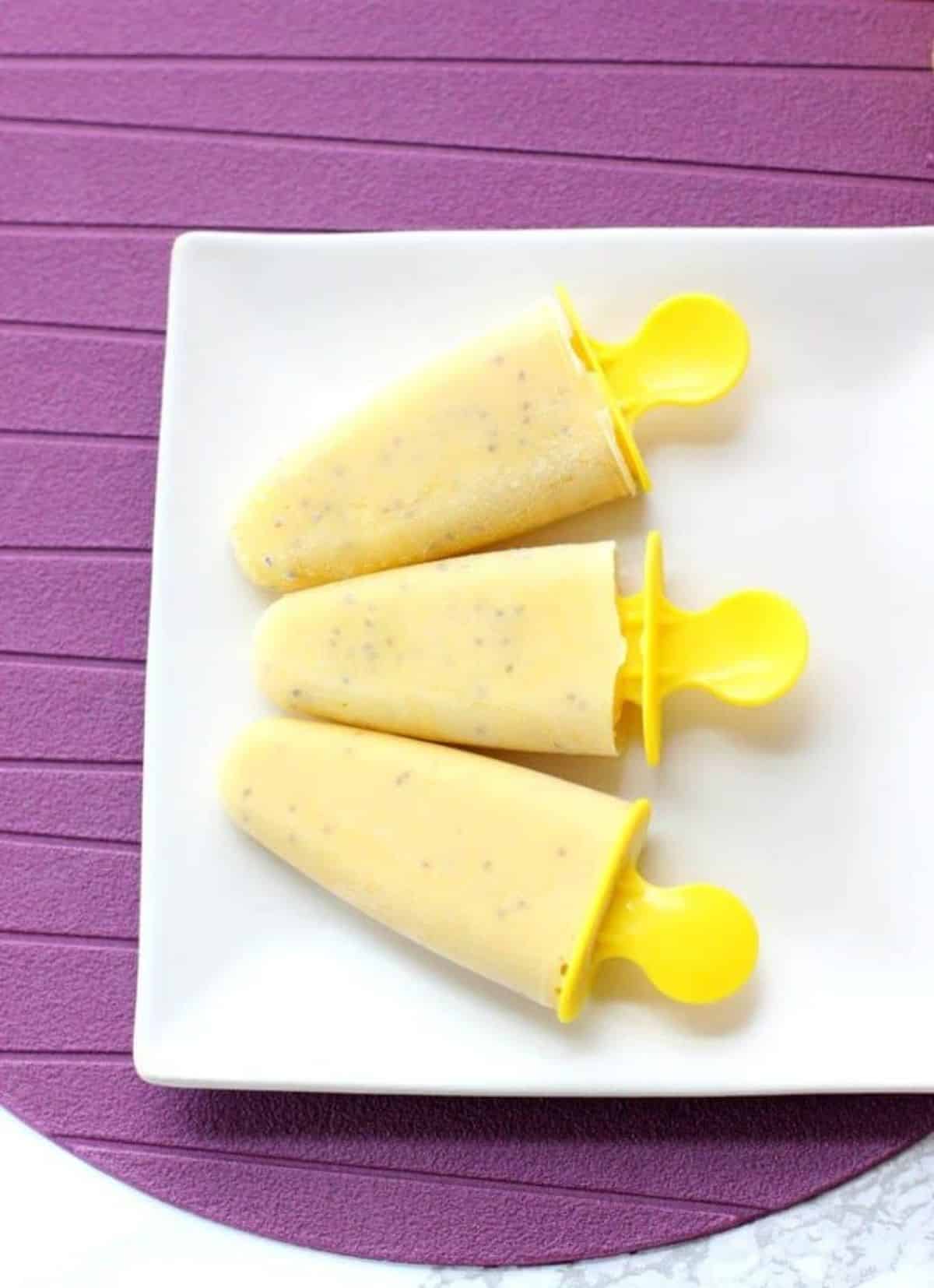 Flavorful frozen pineapple chia ice pops on a white plate.