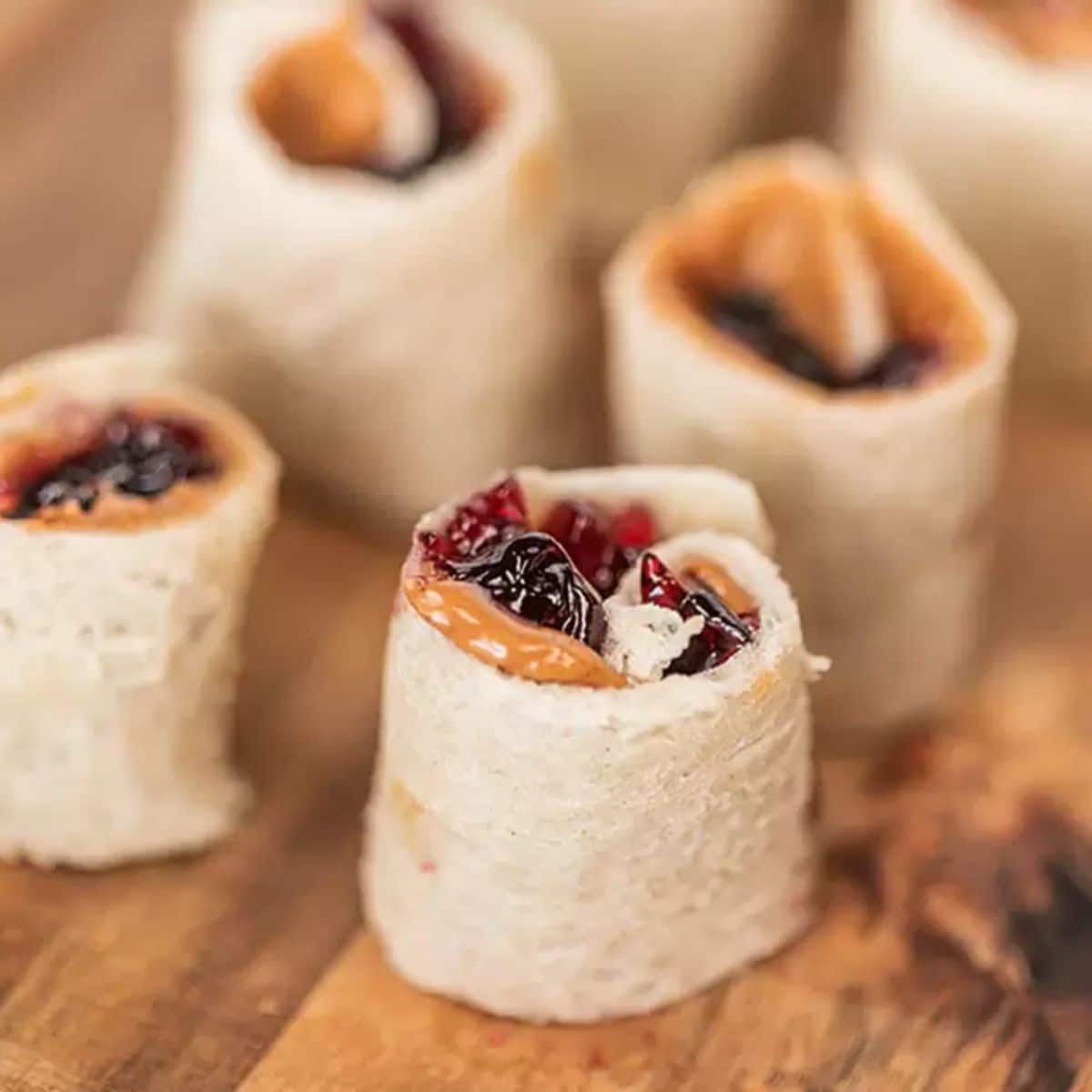 Scrumptious peanut butter and jelly sushi rolls on a wooden table.