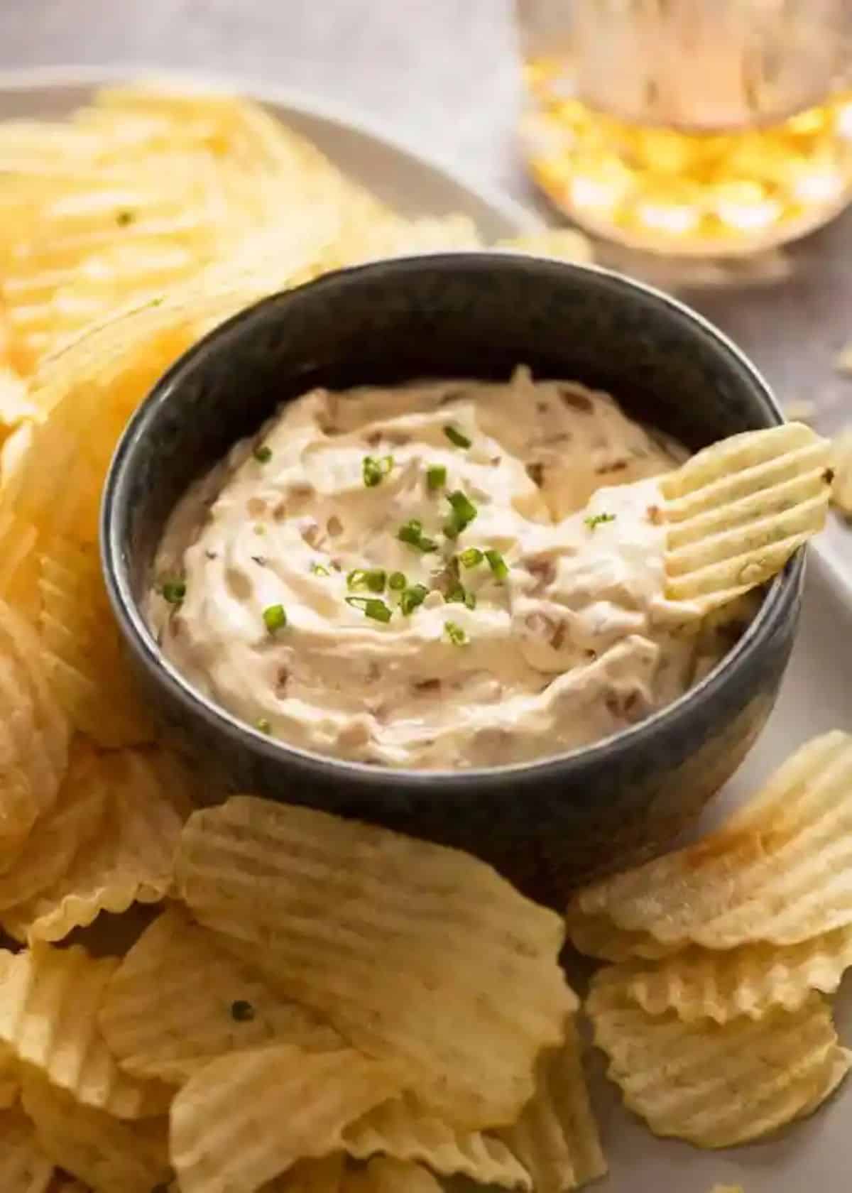Creamy sour cream homemade french onion dip in a black bowl.