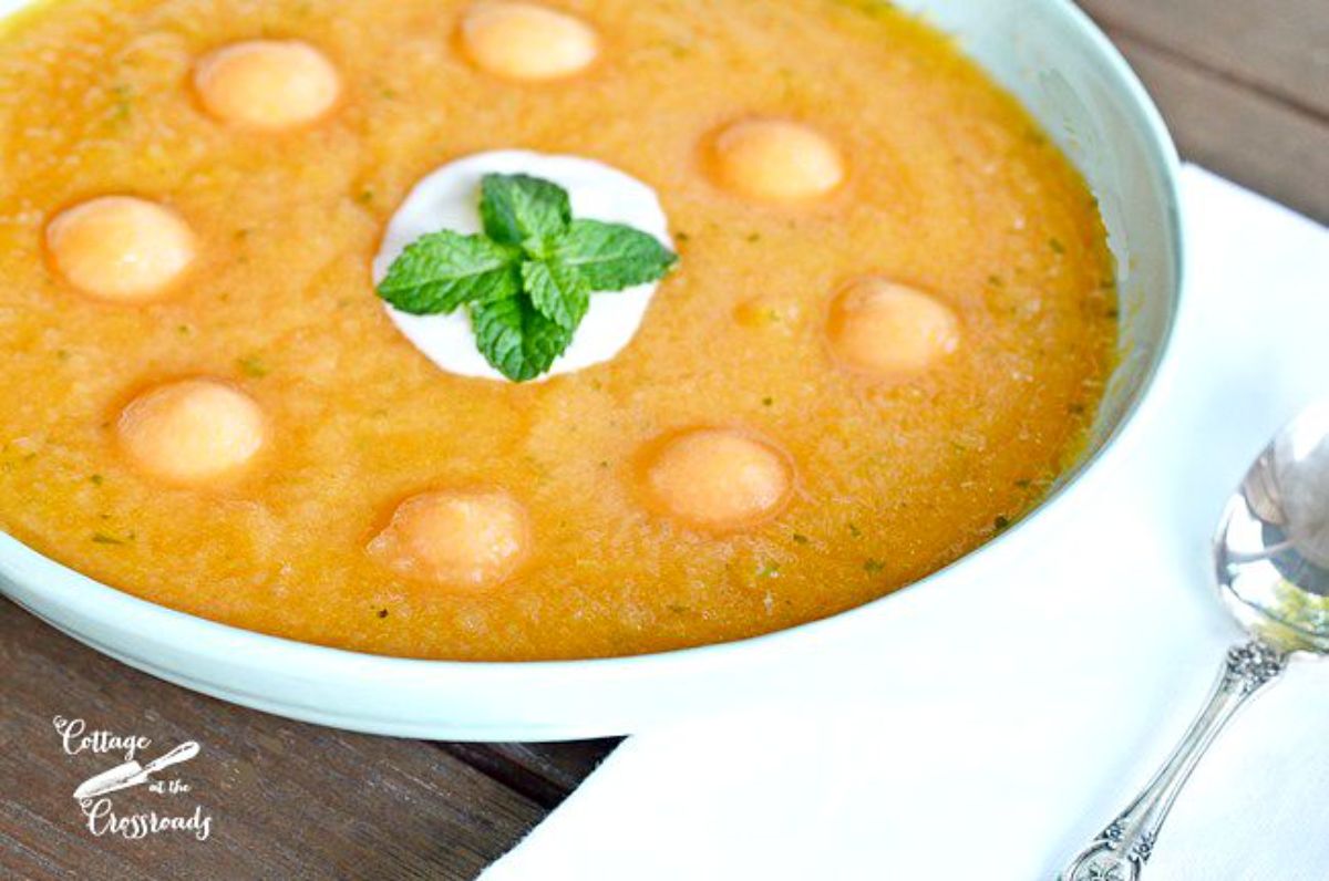 Creamy peachy cantaloup soup in a blue bowl.