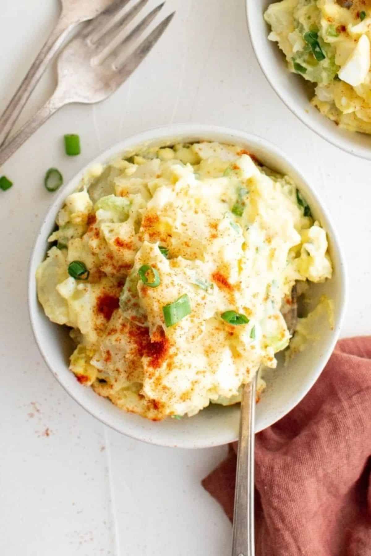 Creamy southern potato salad in a white bowl with a spoon.