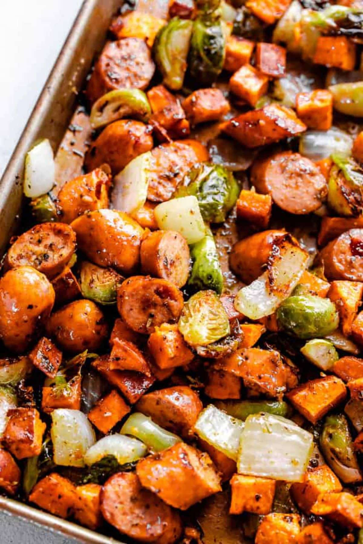 Juicy andouille sausage with sweet potatoes and brussel sprouts in a casserole.