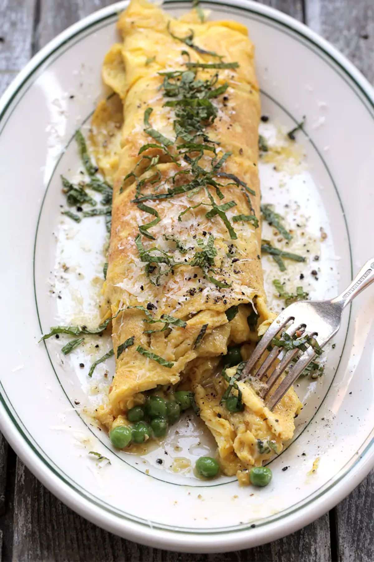 Scrumptious brown butter, peas, and mint omelet on a plate with a fork.