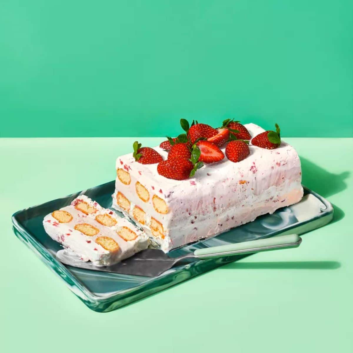 Tasteful strawberry trifle on a metal tray with a spatula.