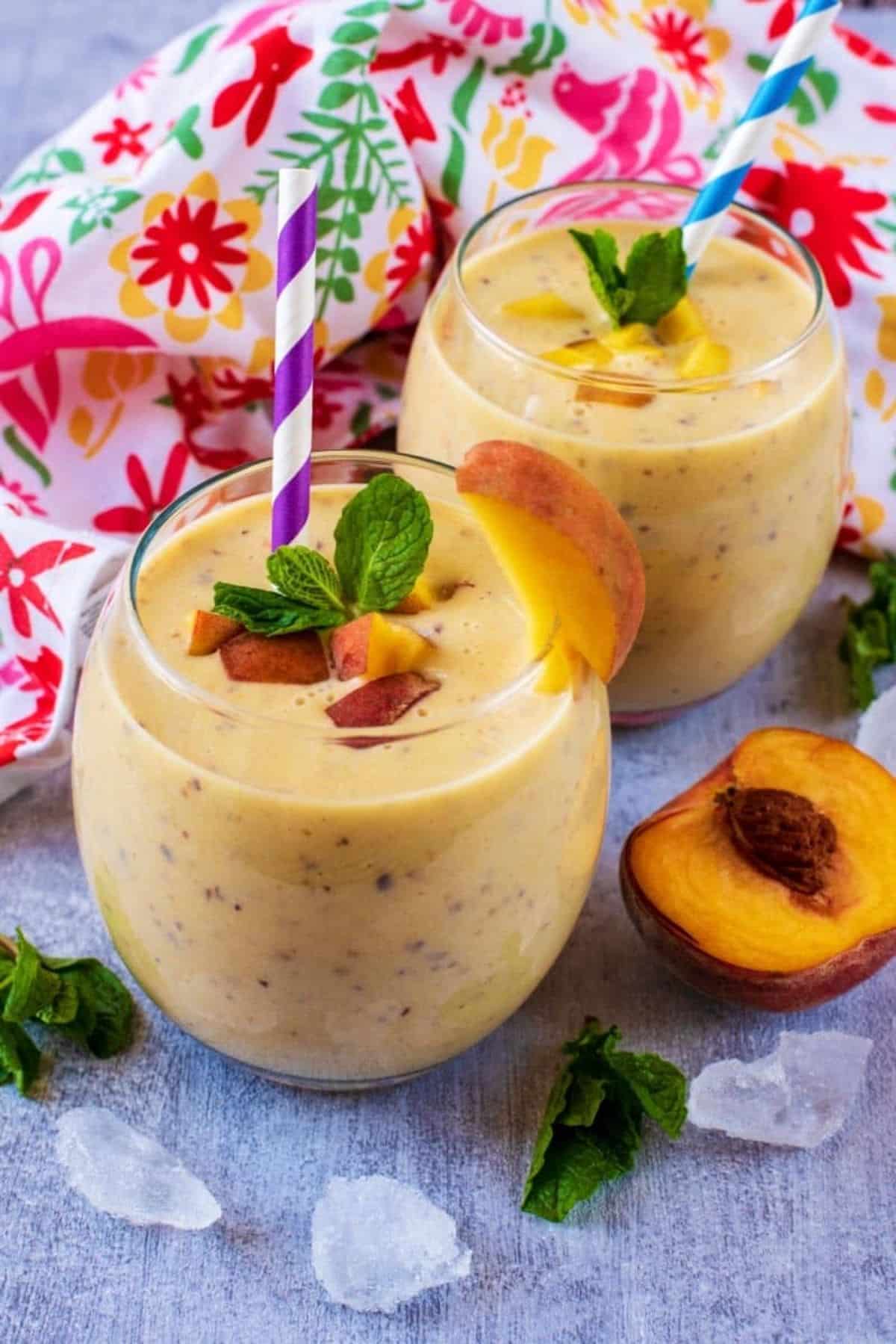 Healthy peach smoothie in glass cups with straws.