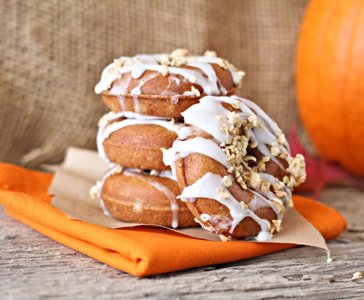 A pile of pumpkin butter mini donuts on a table cloth.