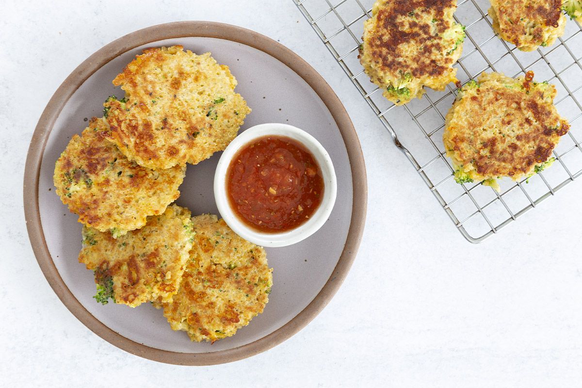 Crispy quinoa patties with a bowl of dip on a plate.