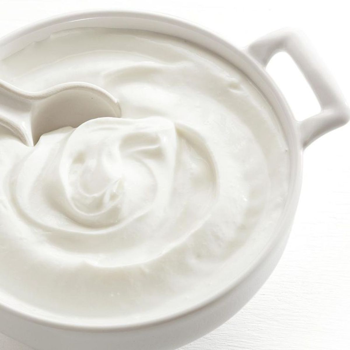 Creamy homemade plain greek yogurt in a white bowl.