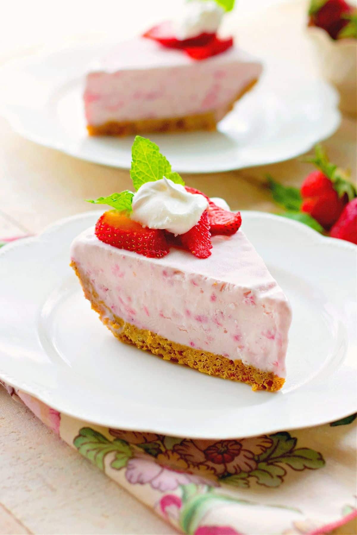 A piece of frozen strawberry cream pie on a white plate.