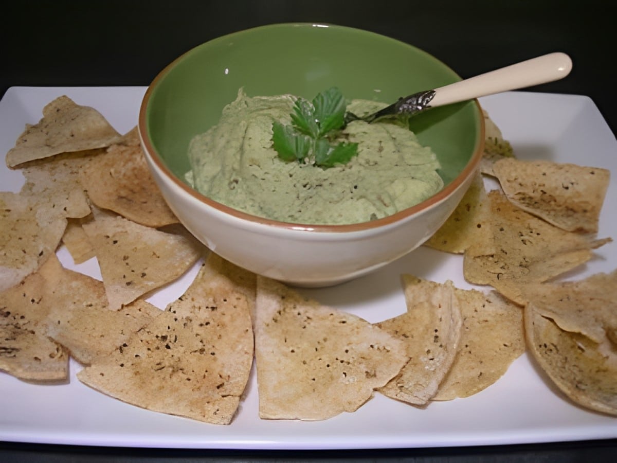 Creamy white bean dip with pita chips on a white tray.