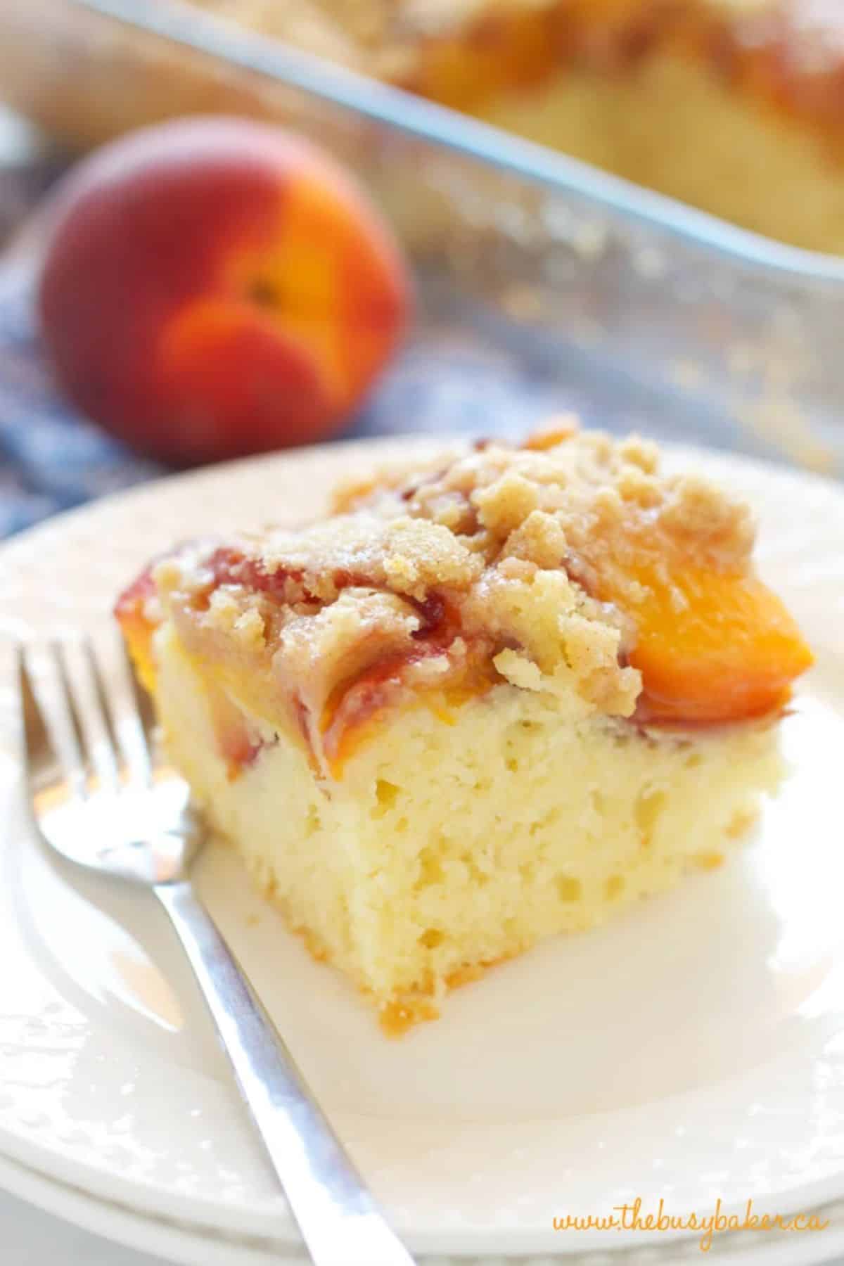 A piece of flavorful peach streusel cake on a plate with a fork.